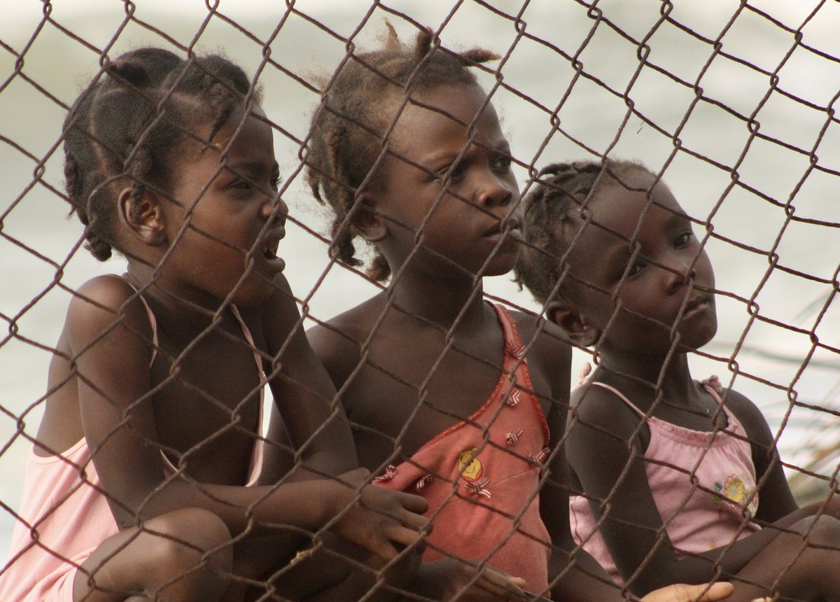 children sitting behind fence