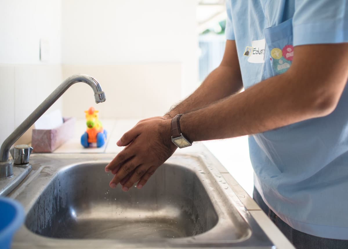 man washing hands in sink