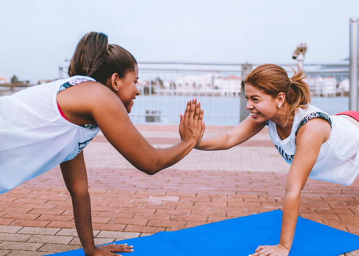 two women in plank pose and high fiving