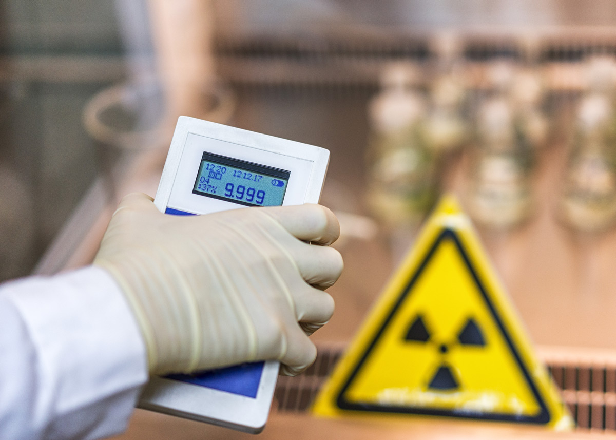 dosimeter in gloved hand with a radiation sign in the background