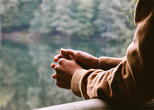 Hands folded and resting on a fence