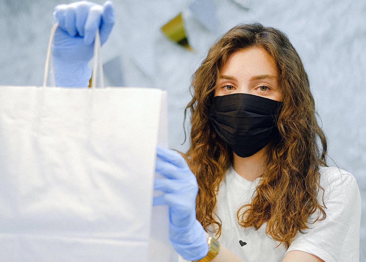 woman holding a takeout bag wearing a mask and gloves