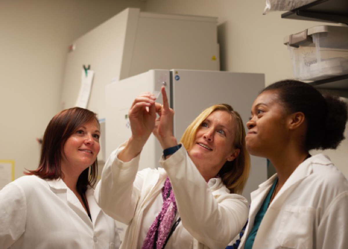 students and Alison Bauer looking at a test tube