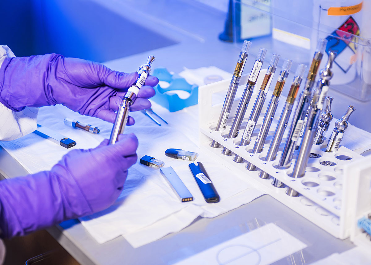 gloved hands of lab tech holding e-cigarette