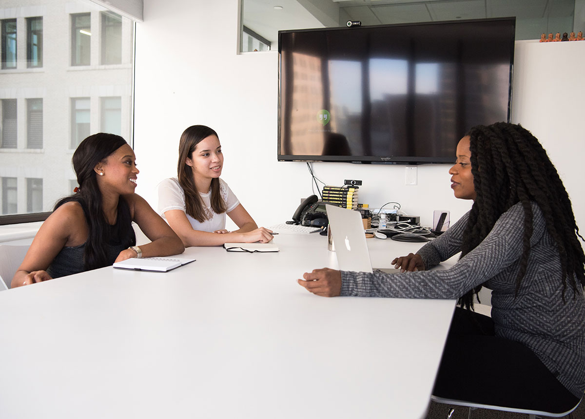 three women sitting at a table in a meeting