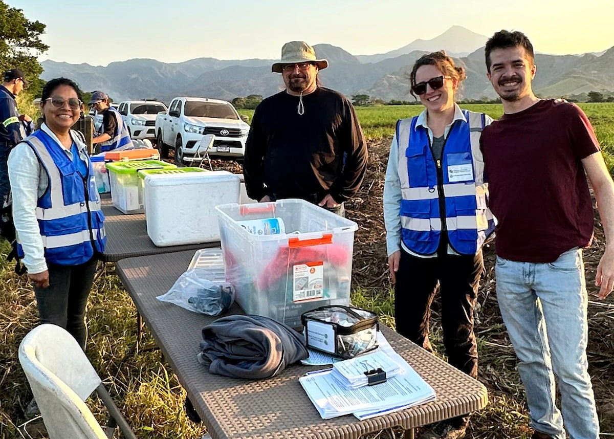 team standing in field with medical research equipment