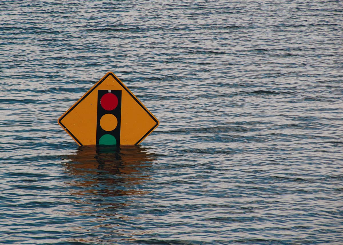 Street sign poking out of water in a flooded street