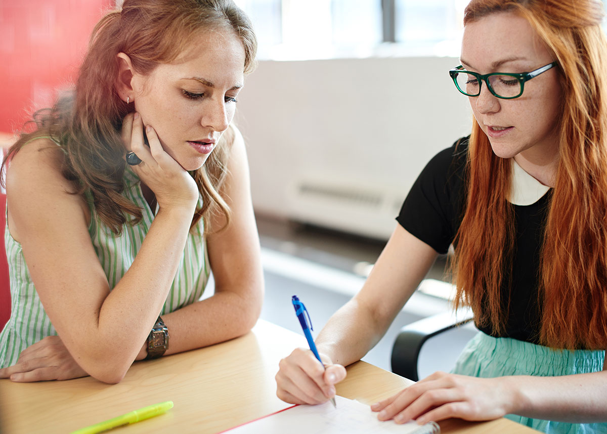 two people talking and writing together