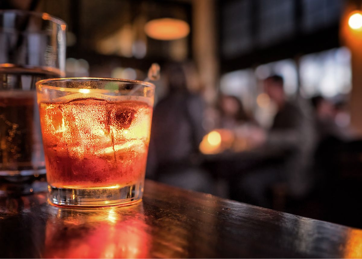 Cocktail close up in a bar setting. Blurred people in the background. Selective focus on the icy drink and glass.