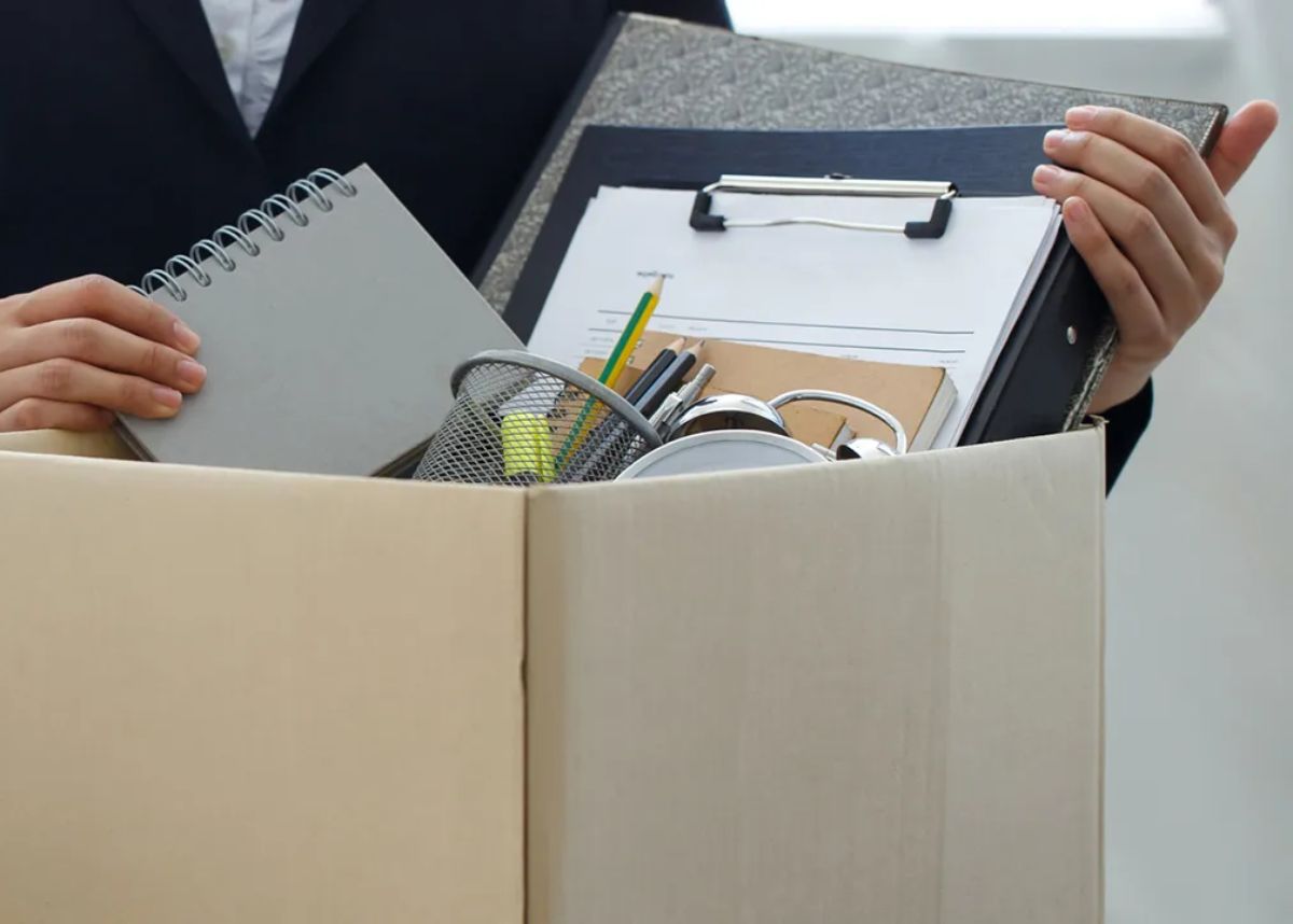 Person in suit packing away there work things in a box with a tone of being let go