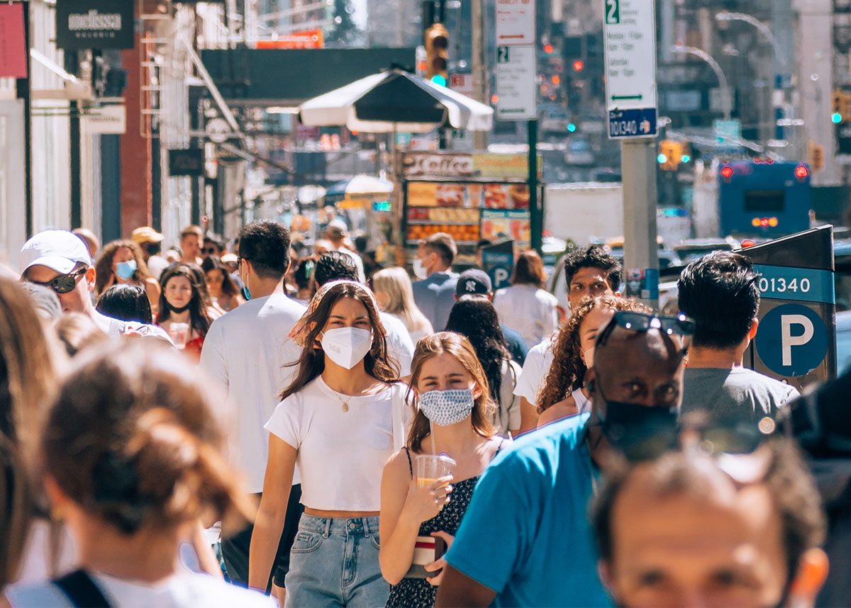 Crowd of people walking, some wearing masks