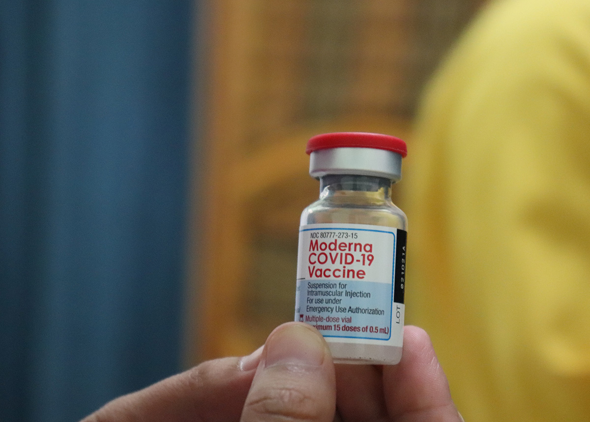 Close up of a person holding a vial labeled 