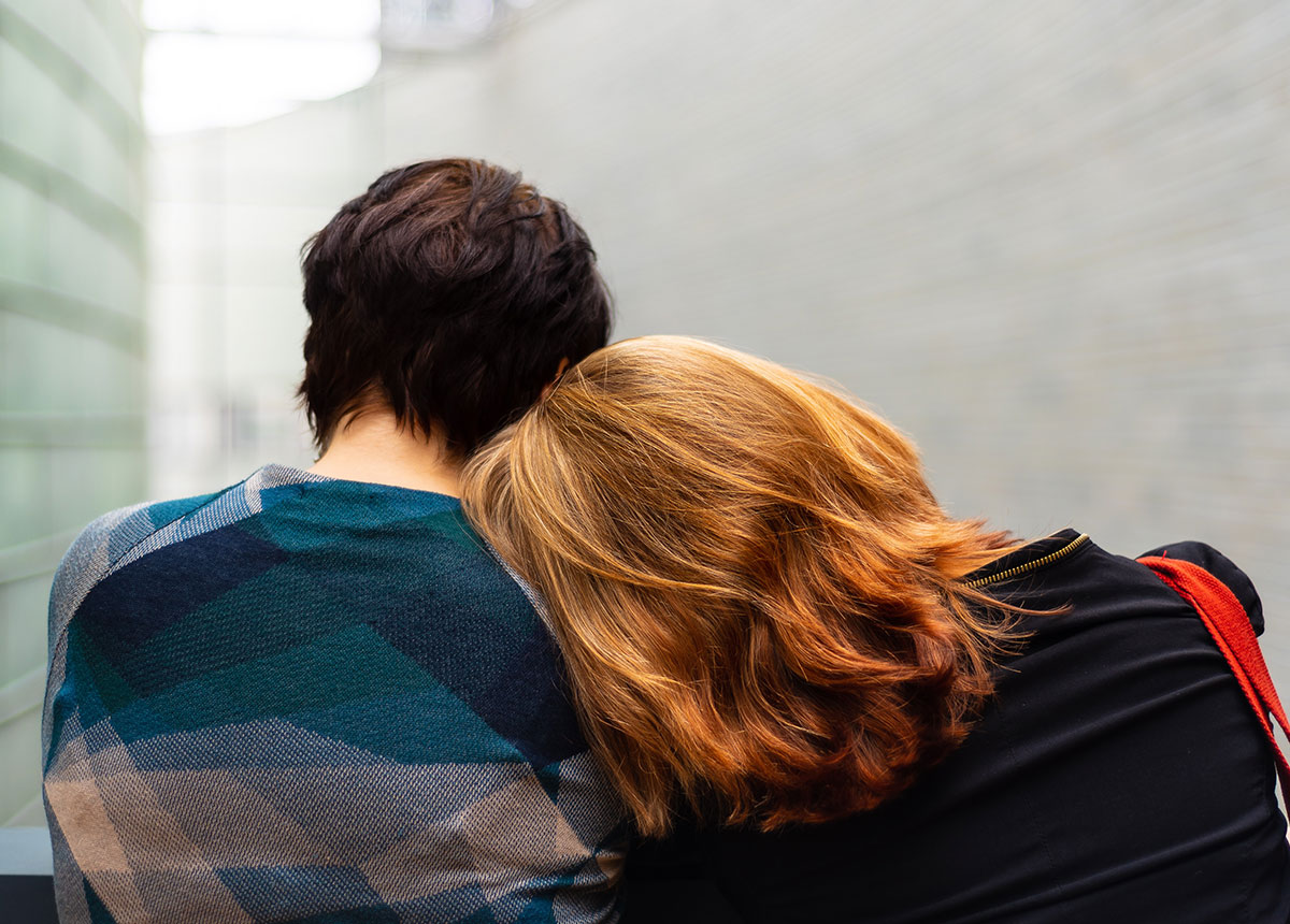 person resting their head on another person's shoulder