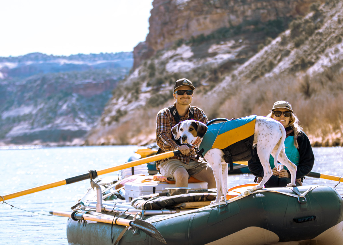 two people and a dog in a raft on a lake