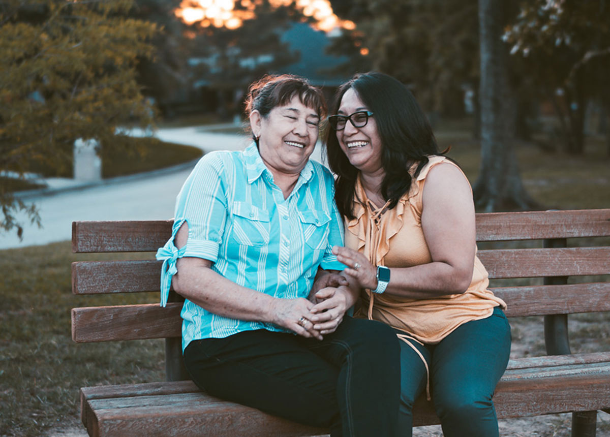 two women laughing sitting on a bench