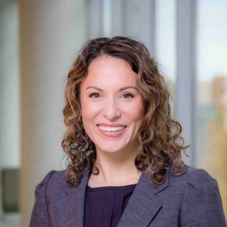 Woman smiling in headshot wearing dark blazer and shirt