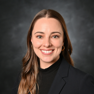 Woman smiling in headshot on gray background