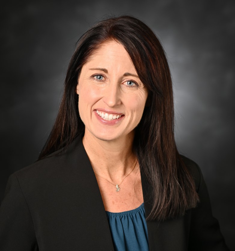 Headshot of woman wearing teal shirt and black jacket