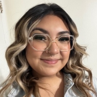 Woman smiling in headshot wearing glasses with curled hair