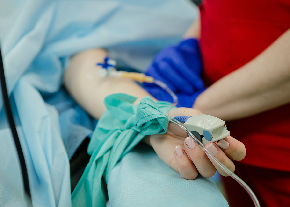 Close up of hospitalized person's hand with IV and finger pulse