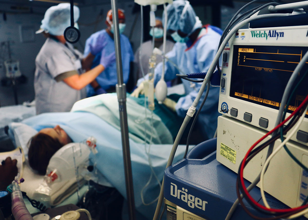 Patient in hospital bed surrounded by medical professionals and equipment