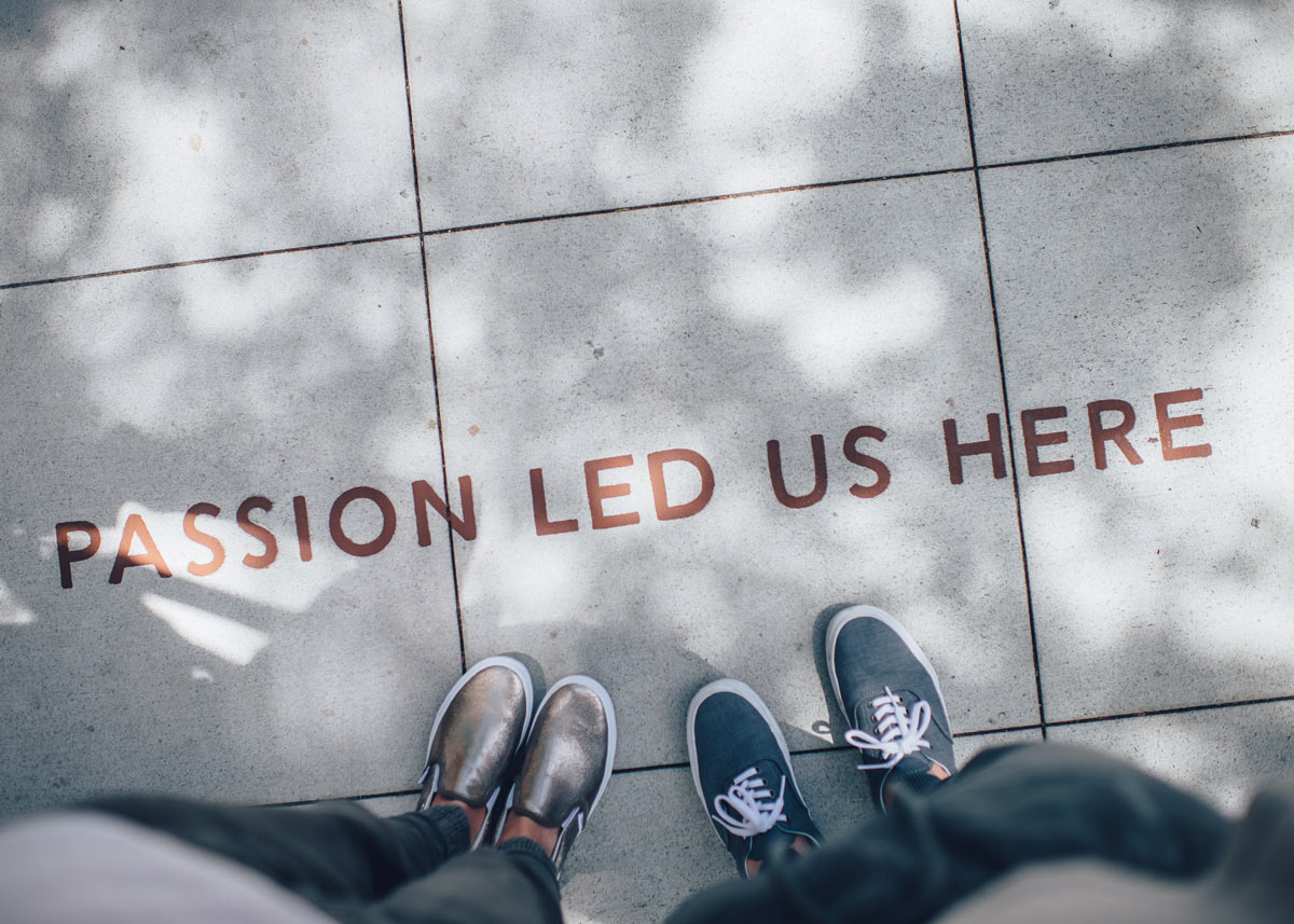 two people's feet on sidewalk with writing that reads 