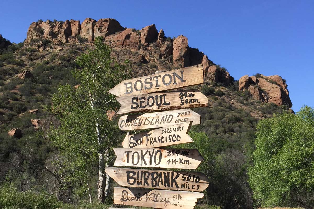 wood direction signs with rocky landscape and trees in background