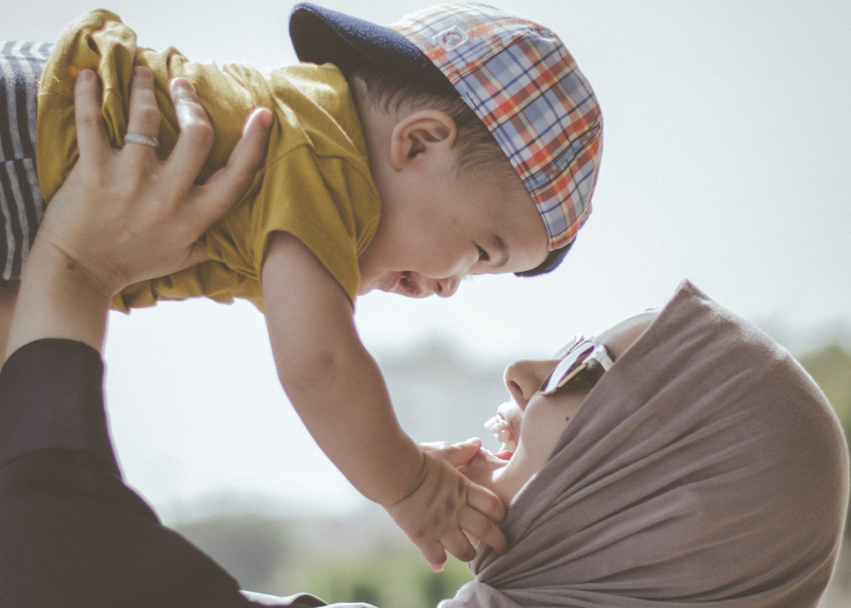 woman holding a smiling child in the air above her head