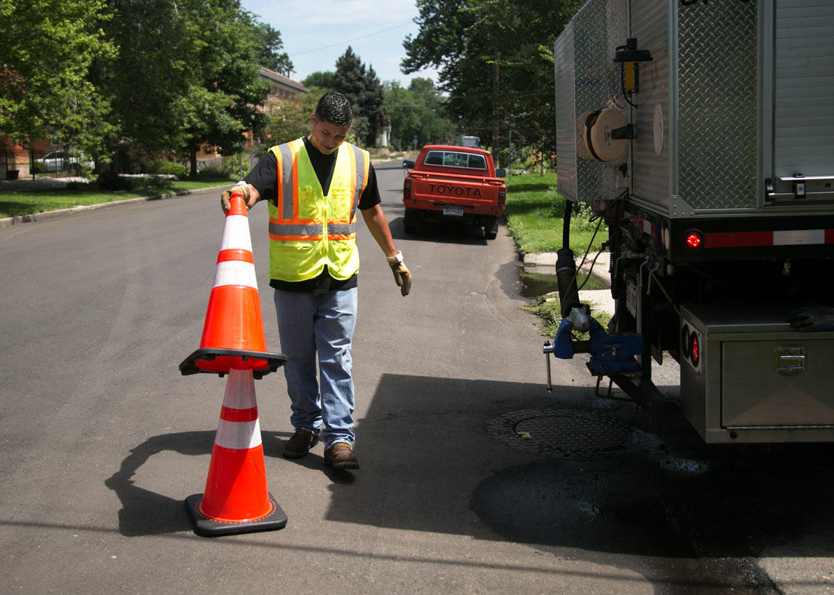 worker putting a traffic cone on top of another cone