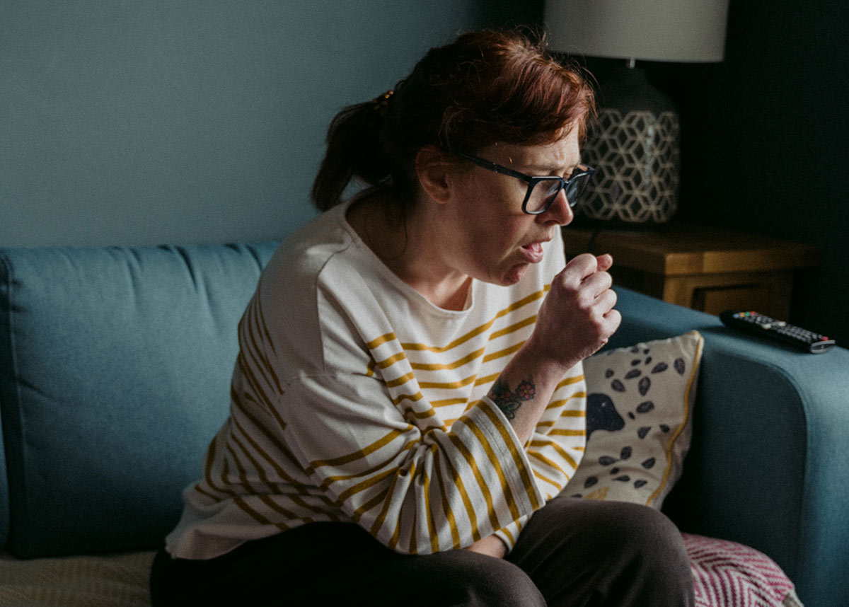 woman coughing and sitting on a couch