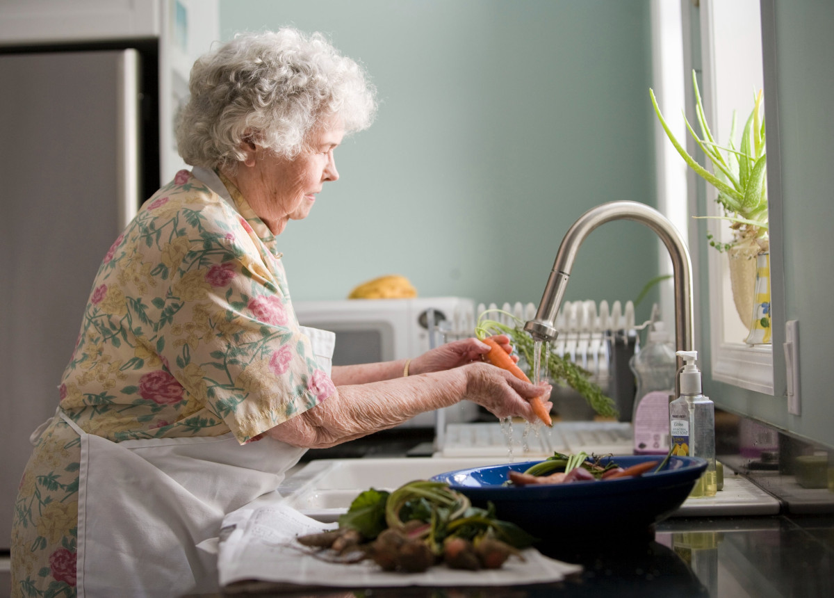 elderly woman washing vegetables