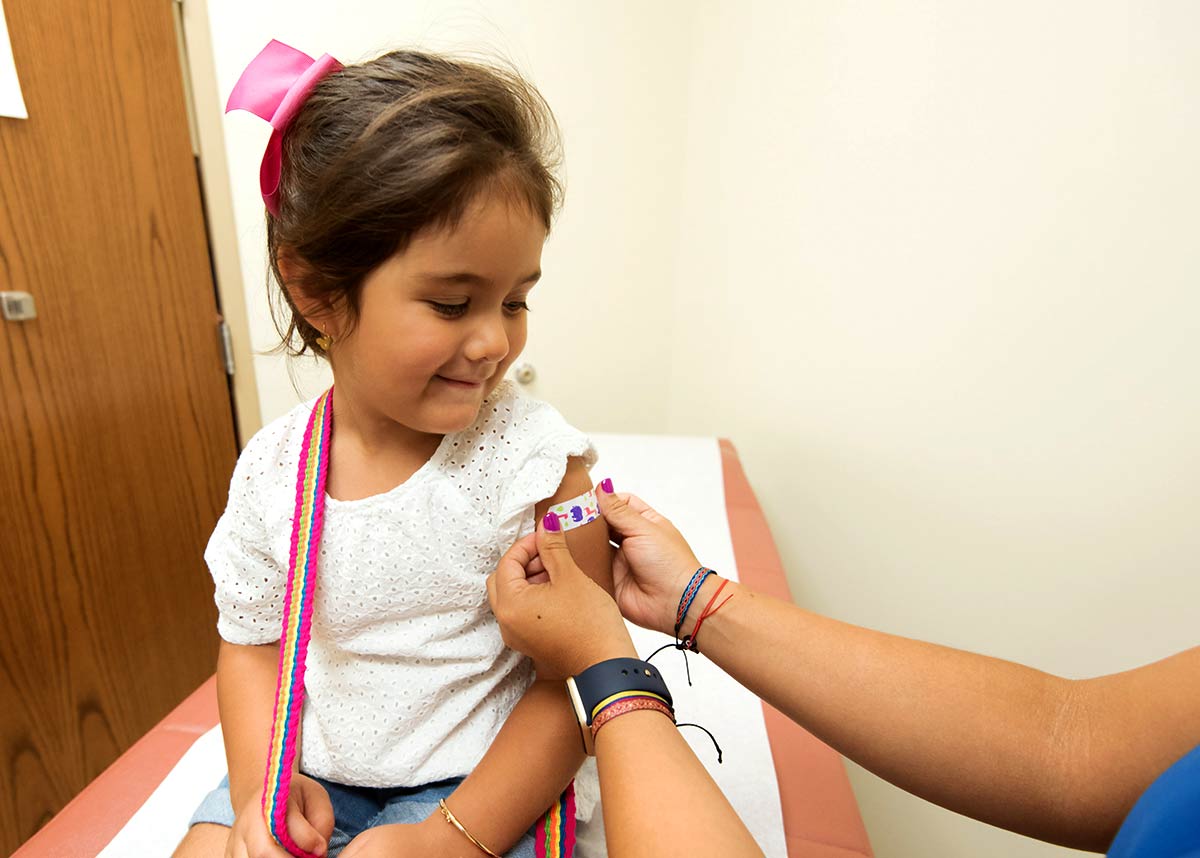 child in doctor's office getting a bandaid put on her arm