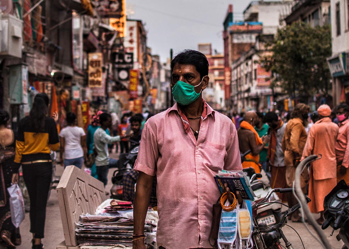 man in a mask walking through busy streets in India