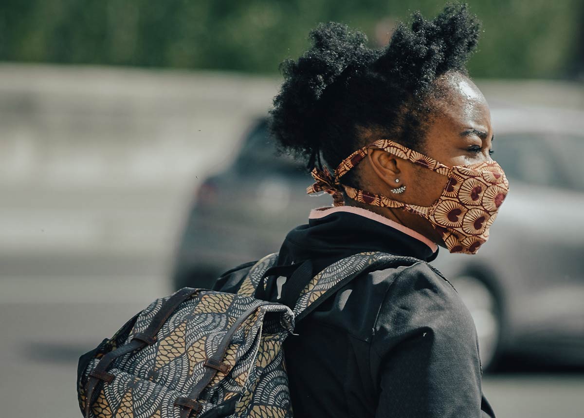 woman with a backpack and face mask on walking