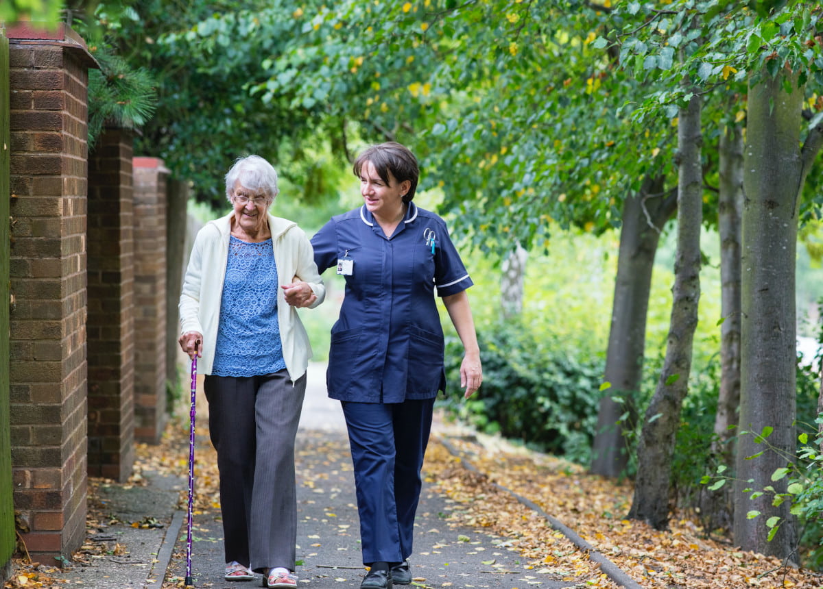 elderly woman and nurse walking down street