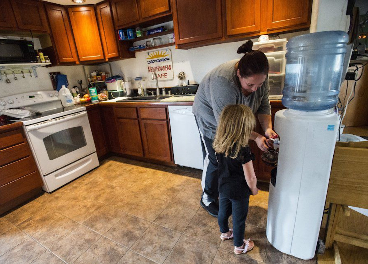 mom and daugther drinking water from filtering system