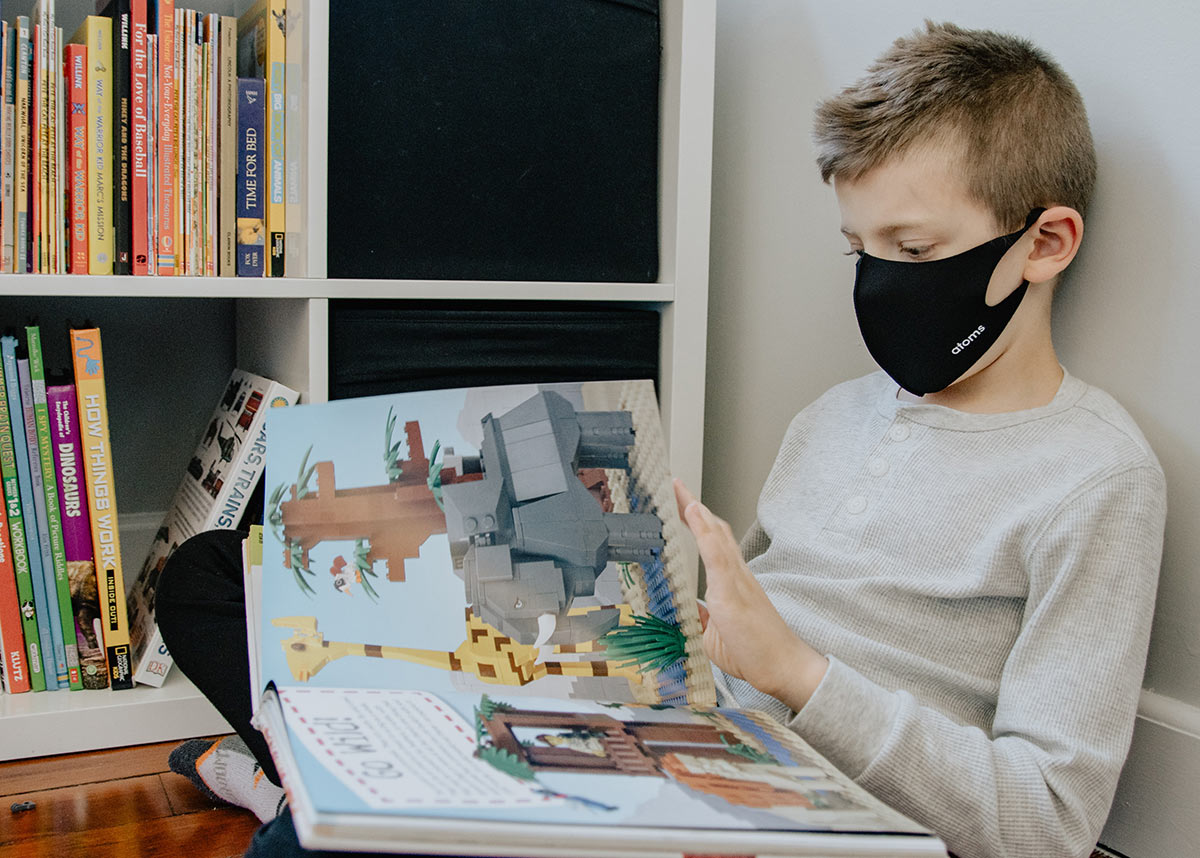 child in a mask reading a book