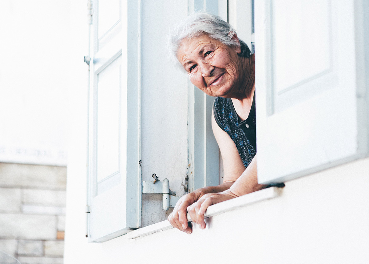 older adult woman sticking her head out of a window