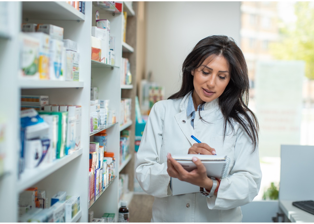 Woman wearing white lab coat writing in notebook