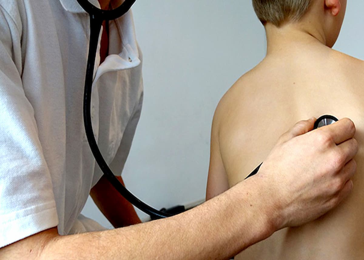 Doctor checking boys lungs with stethoscope 