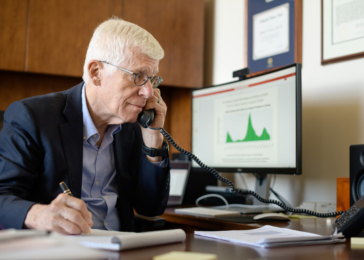 Dean Jon Samet working at a desktop displaying COVID data