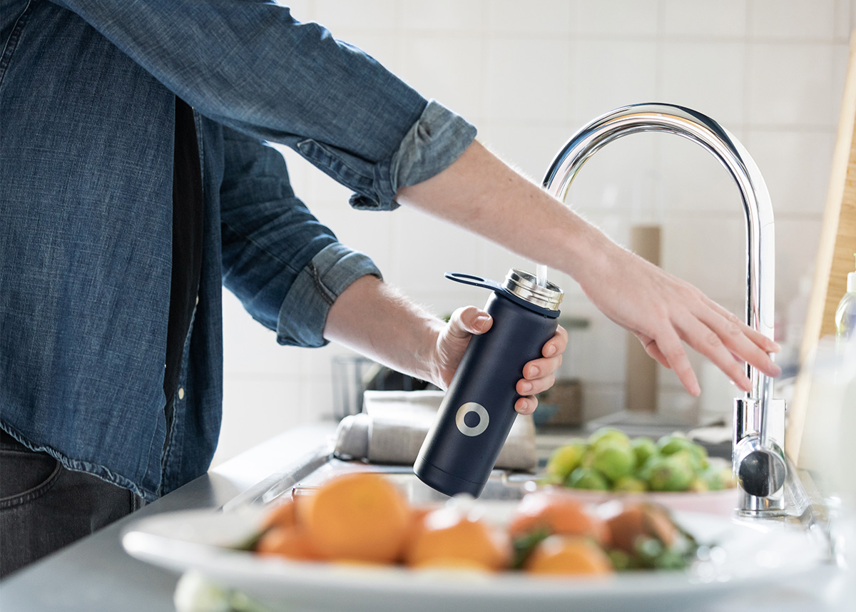 Person filling reusable water bottle with tap water