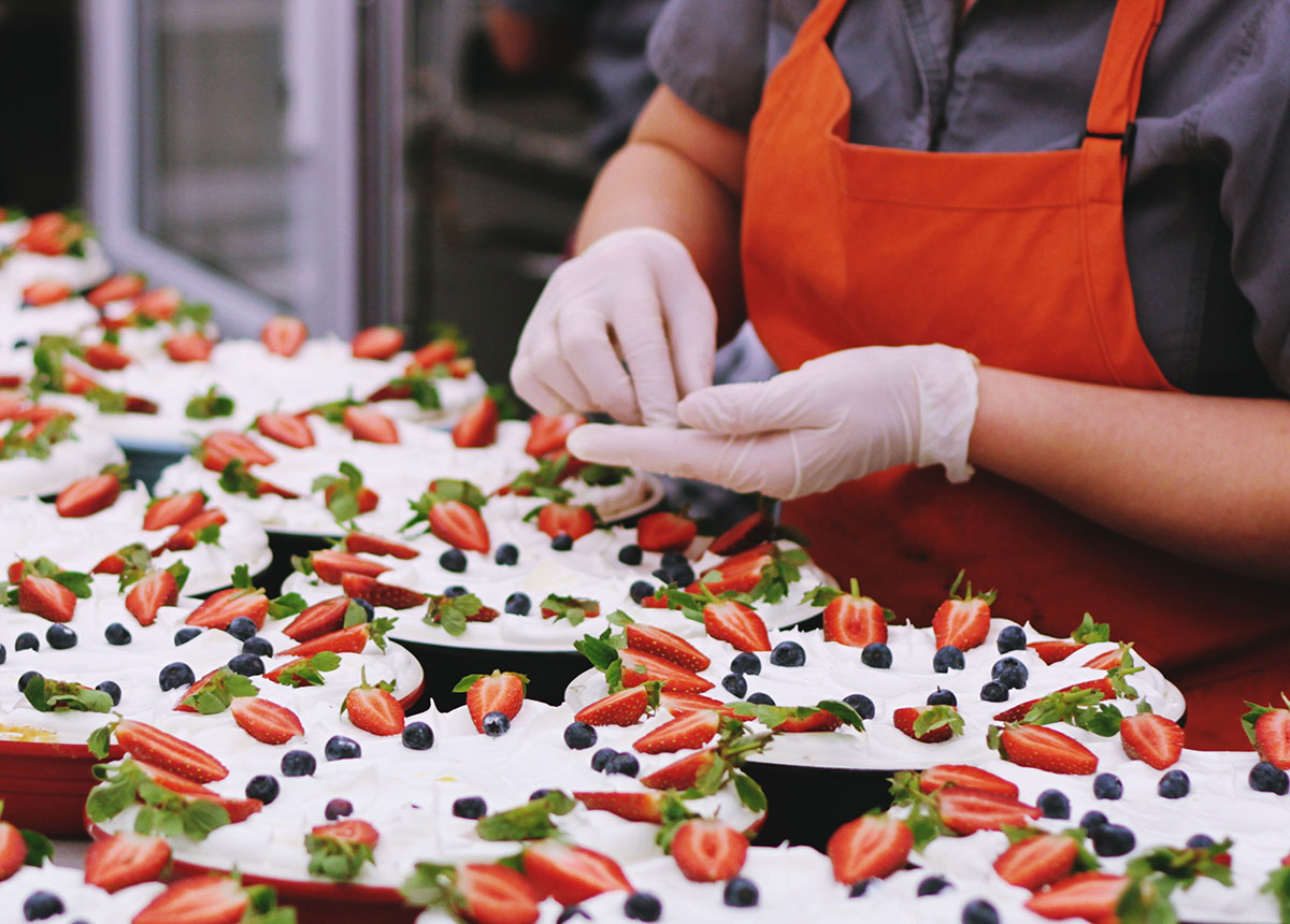 gloved hands placing berries plates