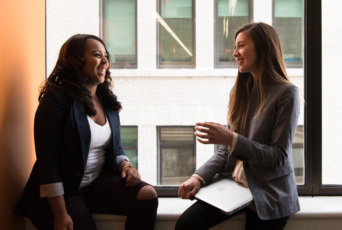 two professionals sitting on a window sill talking