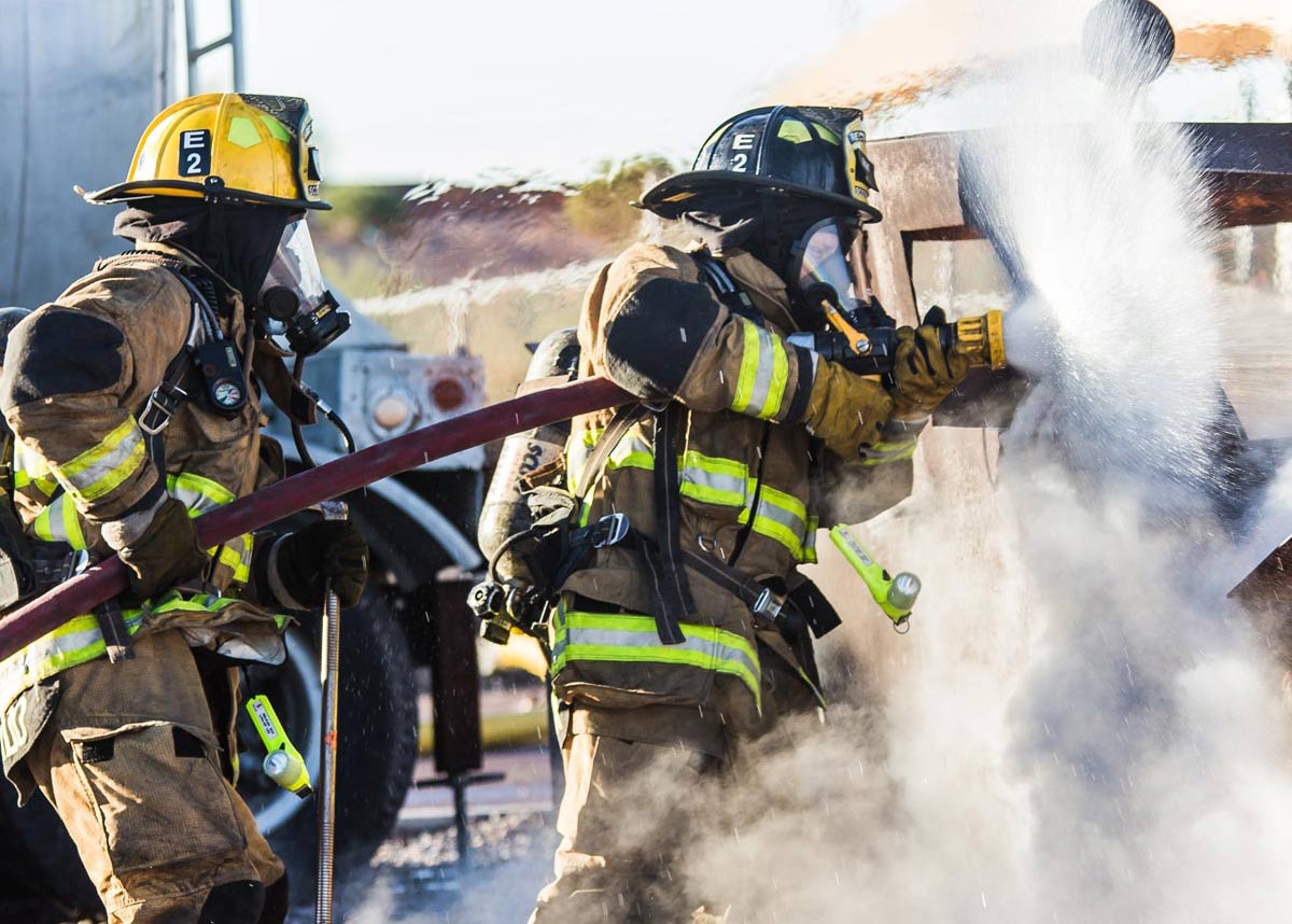 two firefighters spraying water on a fire