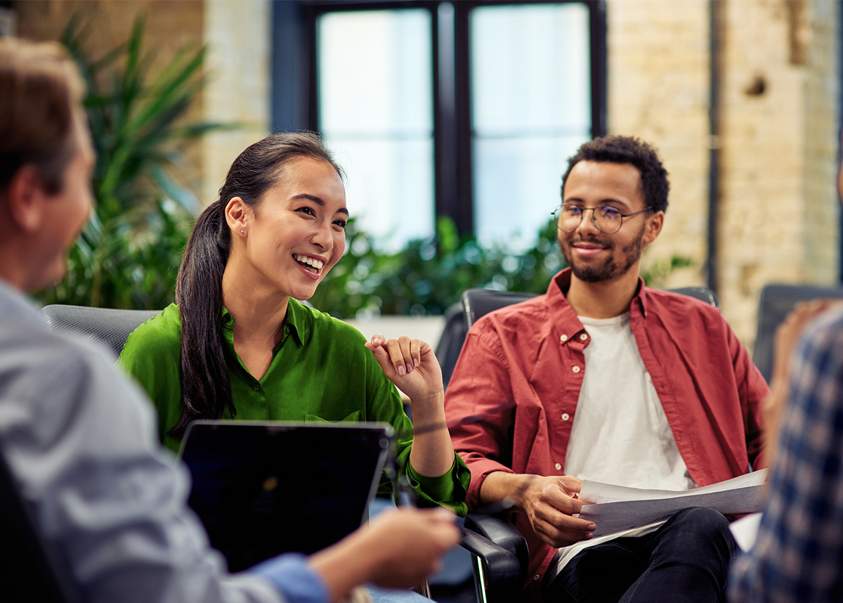 Two coworkers smiling and chatting, seated at a meeting