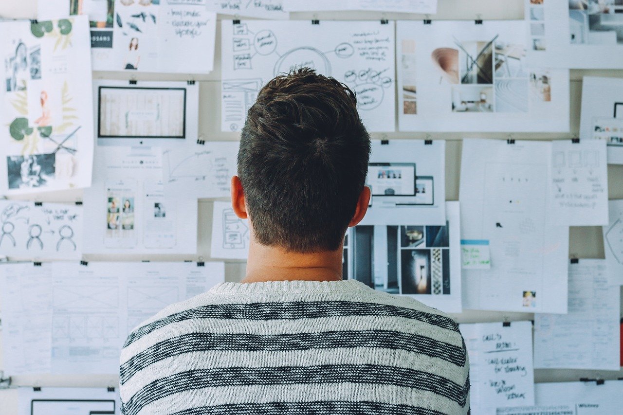 man looking at papers on wall