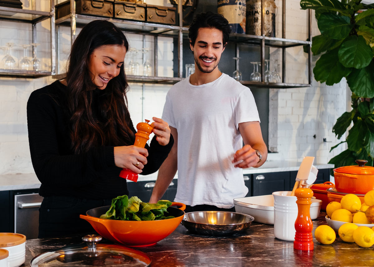 man and woman making a salad in a kitchen