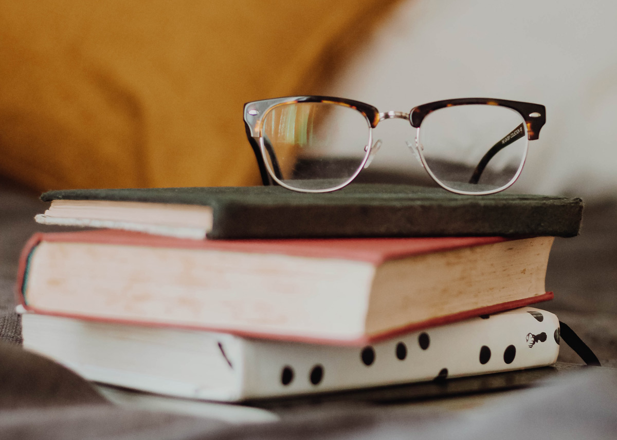 stack of books with eyeglasses on top