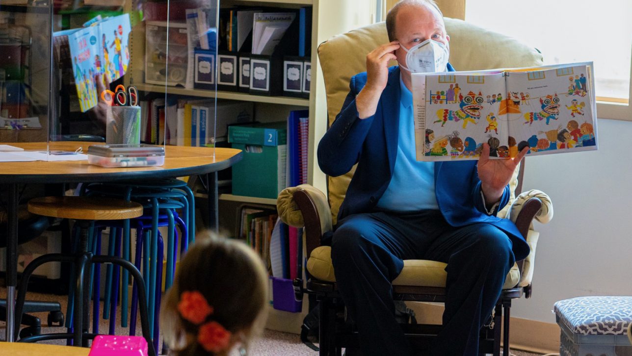 Jared Polis, the governor of Colorado, reads to a young student.